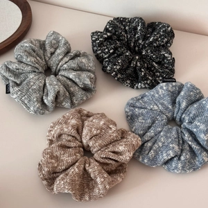 Detail of four knitted oversized scrunchies in mixed colors with woven fashion labels