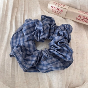Detail of blue and white plaid scrunchie with textured cotton fabric on beige cloth