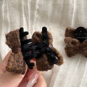 Detailed macro view of the brown wool fabric bow and black plastic claw clip texture