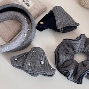 Close-up of gray knitted hair accessories set with rhinestones and pearl details