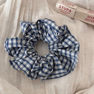Detailed view of blue and white plaid fabric scrunchie with soft ruffled texture
