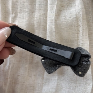 Detail of grey wool bow hair clip with black felt lining and secure metal fastener