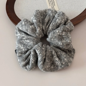 Macro detail of grey and white knitted scrunchie showing fine yarn texture and side label