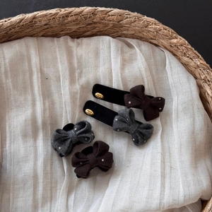Detailed close-up of knitted bow hair clips with polka dots and handmade gold metal tag