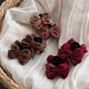 Close-up of knit bow hair clips in coffee and burgundy colors on a woven basket