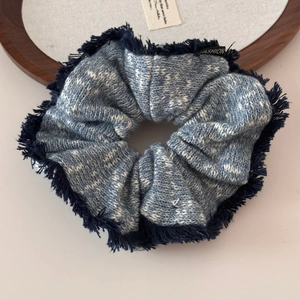 Close-up of blue and white knitted oversized scrunchie with fringe texture details