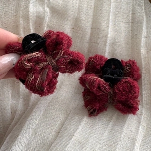 Close-up of deep red wool bow hair clips with soft plush texture and black claw grip