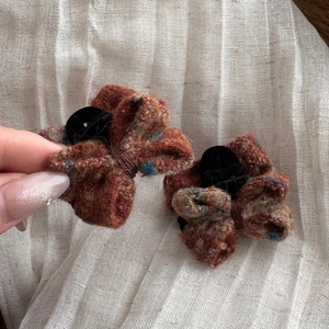Detail view of tweed bow hair clips with red and blue fabric texture and black velvet center