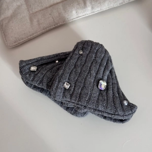 Detail of dark grey knitted hair clip with sparkling rhinestones and white pearl texture