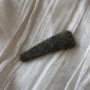 Close-up of textured dark green felt fabric hair clip on soft white gauze background