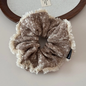 Detail of a large knit scrunchie with mixed brown wool and white fringe edges