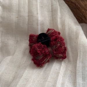 Detailed close-up of a burgundy knitted bow hair clip featuring a rich wool texture