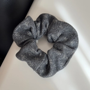 Close-up of gray felt scrunchie featuring white snowflake patterns for winter hairstyle