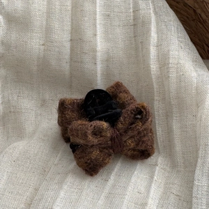 Detail view of the brown wool bow hair claw clip showing soft knit texture and design
