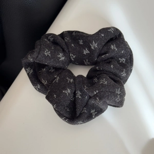 Close-up of dark grey floral scrunchie with white leaf patterns and plush texture