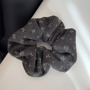 Close-up of dark grey floral scrunchie with soft fabric texture and vintage white patterns