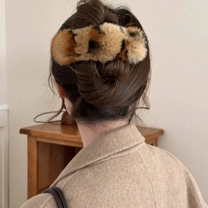 Gros plan d'une pince à cheveux élégante en peluche léopard sur une coiffure souple