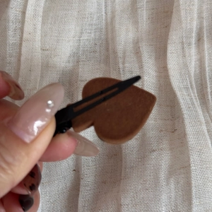Detail of a brown heart-shaped flocking hair clip with matte texture on duckbill clip