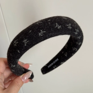 Detail view of handmade black felt headband featuring white snowflake floral embroidery