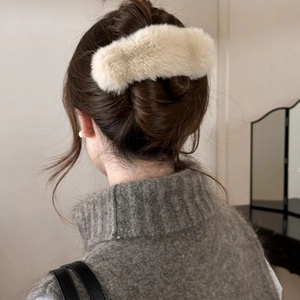 Vue détaillée d'une pince à cheveux élégante en fausse fourrure crème sur un chignon