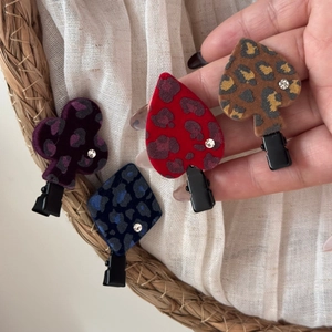 Detail of leopard print hair clips with poker suit shapes and sparkling rhinestone accents