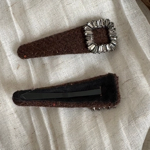 Detail view of brown fabric hair clip with rhinestones and black metal alligator clip