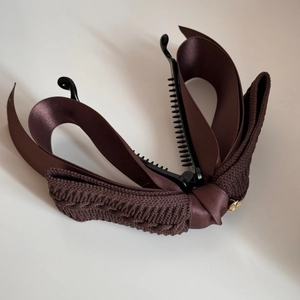 Detail showing non-slip teeth and dual-layer brown ribbon bow on banana hair clip