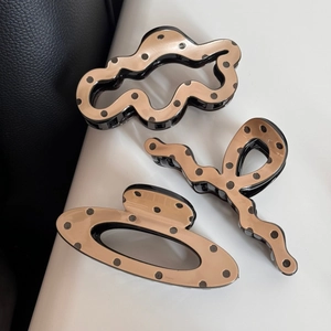 Three assorted beige polka dot hair clips including wavy and oval shapes for styling