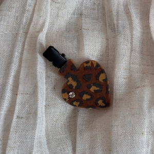 Detail of a leopard print heart hair clip with flocking texture and small rhinestone