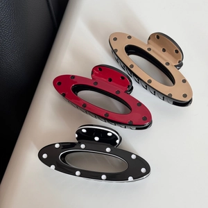 Detailed view of three polka dot hair claws in beige, dark red, and black resin finish