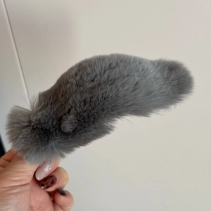 Détail d'une pince à cheveux en peluche grise montrant sa texture douce et sa forme longue