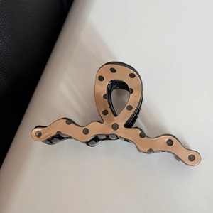 Close-up of khaki polka dot hair claw clip with irregular wave design and metal spring
