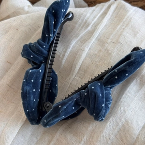 Detail view of blue velvet polka dot banana hair clips on a linen background