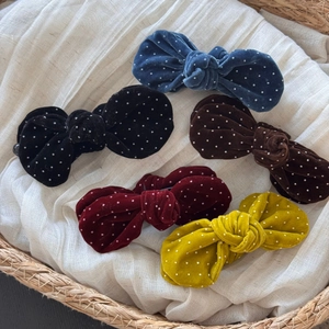 Five-piece velvet polka dot bow hair clip set in various colors on a rustic basket