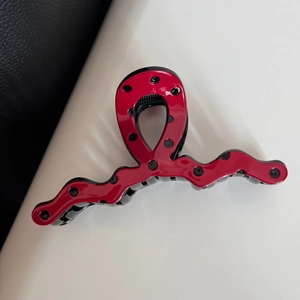 Close-up of red and black polka dot hair claw clip with glossy finish and wavy edge