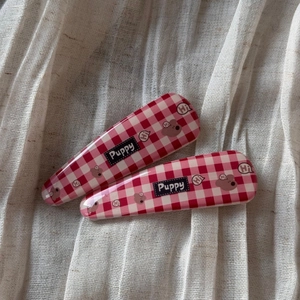 Détail de barrettes à carreaux rouges et blancs avec motif ours sur tissu blanc