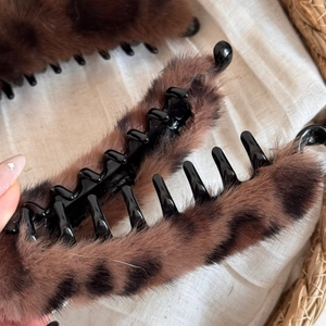Détail de la pince à cheveux en peluche léopard avec une texture douce en fausse fourrure