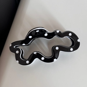 Detailed view of the wavy black hair claw clip featuring classic white polka dots