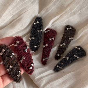 Detail of winter wool hairpins featuring silver metal bows in deep red and black colors