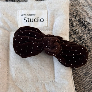 Detail view of a handmade dark brown velvet bow hair clip with white polka dots