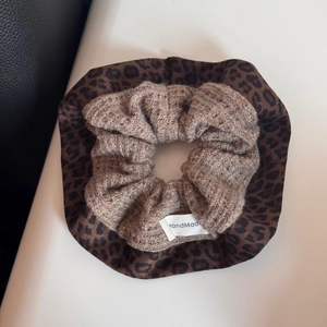 Close-up of leopard print scrunchie and beige knitted hair tie with handmade label