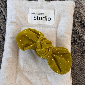 Detailed view of yellow velvet polka dot bow hair clip on a beige display card