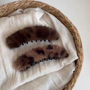 Détail de pinces banane en peluche léopard sur tissu en lin dans un panier