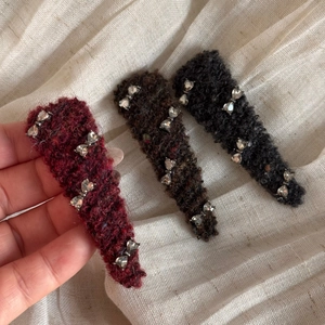 Detailed view of three knitted bow hair clips in burgundy, dark brown, and black colors