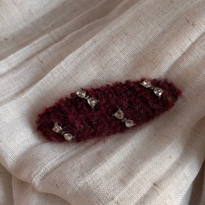 Close-up of a burgundy knit bow hair clip with sparkling heart crystal rhinestone accents