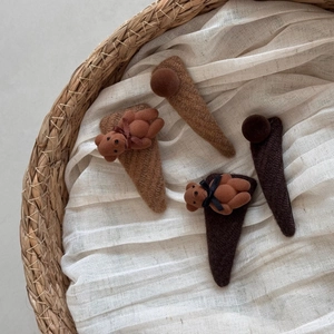 Detail of four brown plush bear and knit fabric triangle hair clips in a woven basket