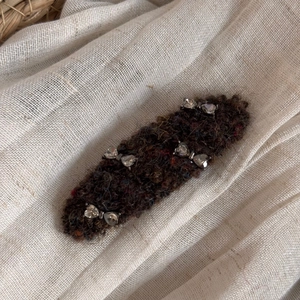 Detail of a brown wool felt hair clip decorated with sparkling rhinestone hearts