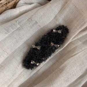 Close-up of black fuzzy wool hair clip featuring four elegant silver metal bow accents