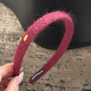 Détail d'un serre-tête en mohair rose tressé à la main avec étiquette métallique dorée