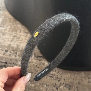 Détail du serre-tête en tricot gris foncé avec plaque dorée Love et étiquette faite main